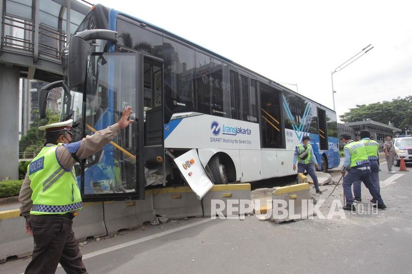 Petugas berupaya mengevakuasi bus TransJakarta yang menabrak separator di Jalan Jenderal Sudirman, Jakarta, Jumat (3/12/2021). Menurut petugas penyebab kecelakaan bus TransJakarta bernomor polisi B 7277 TGC itu diduga akibat sopir yang kurang konsentrasi saat mengemudi. 