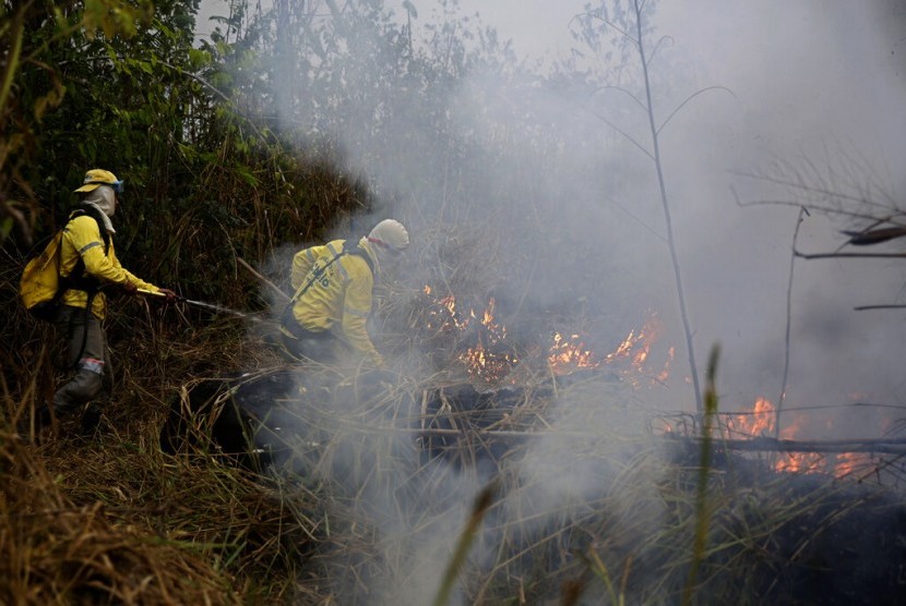 Petugas berusaha memadamkan api di sepanjang jalan ke Jacunda National Forest, dekat kota Porto Velho di kawasan Vila Nova Samuelyang merupakan bagian dari hutan Amazon, Senin (26/8).