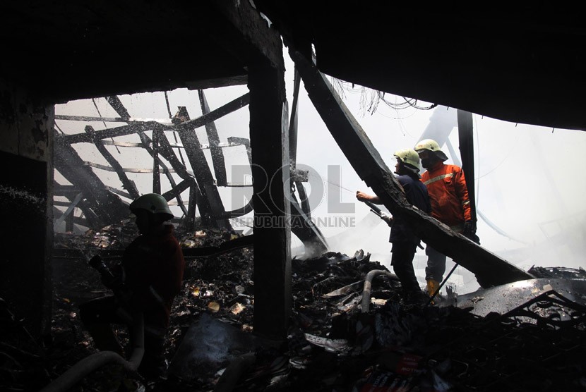  Petugas berusaha memadamkan api saat terjadi kebakaran di sebuah gudang ban, Pluit, Jakarta Utara, Senin (14/10).   (Republika/Yasin Habibi)
