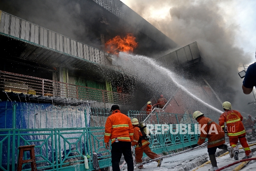 Petugas berusaha memadamkan api yang membakar bangunan Blok I dan Blok II yang terbakar di Pasar Senen, Jakarta, Kamis (19/1).