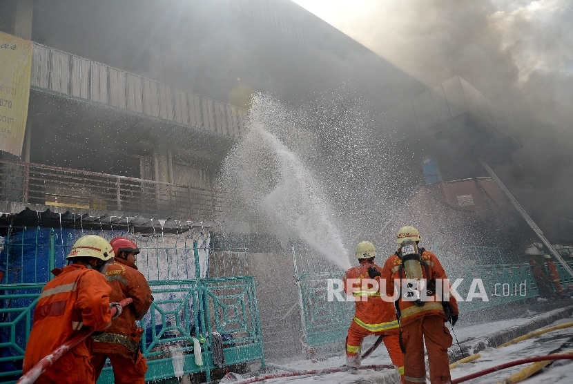 Petugas berusaha memadamkan api yang membakar bangunan Blok I dan Blok II yang terbakar di Pasar Senen, Jakarta, Kamis (19/1).