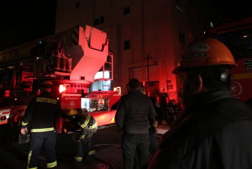 Petugas berusaha memadamkan api yang membakar kantor hak asasi manusia di Israel, Ahad (10/1),