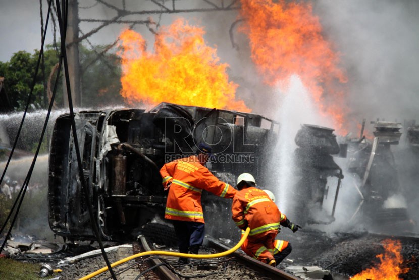   Petugas berusaha memadamkan mobil tangki yang terbakar, setelah ditabrak KRL Commuterline jurusan Serpong-Jakarta di perlintasan kereta di Bintaro Permai, Tangerang Selatan, Senin (9/12). (Republika/Yasin Habibi)