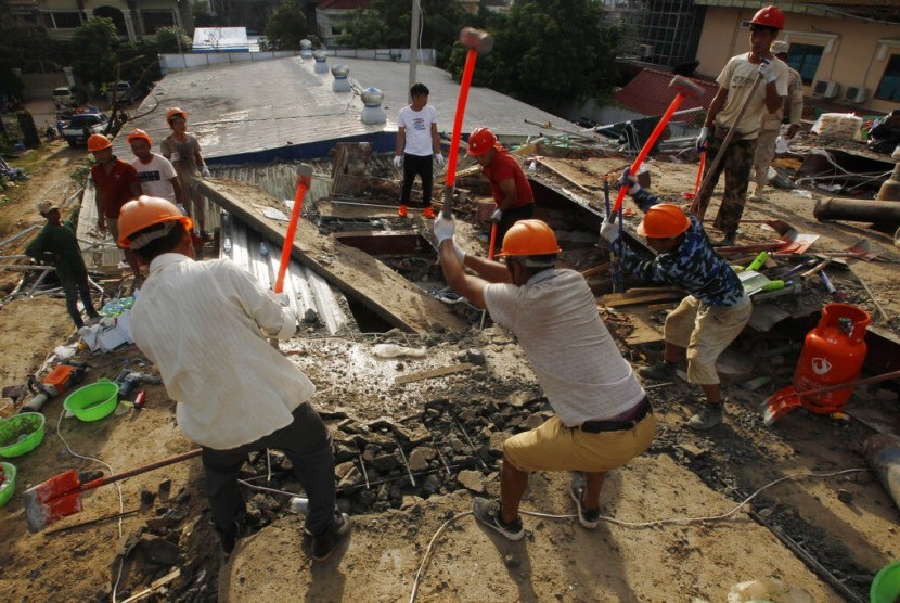 Petugas berusaha membersihkan puing di lokasi pembangunan gedung tujuh lantai yang ambruk di Preah Sihanouk, Kamboja, Ahad (23/6).