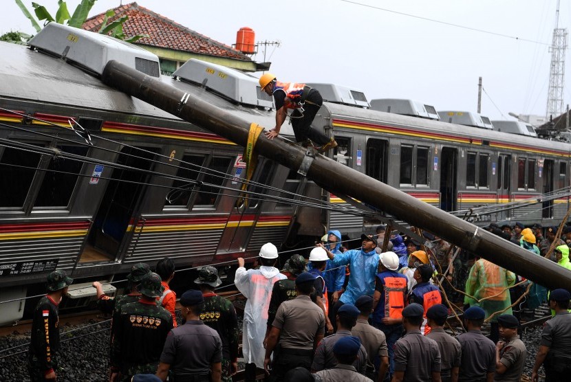 Petugas berusaha memindahkan tiang listrik yang menimpa gerbong KRL Commuter Line 1722 yang anjlok di pintu perlintasan Kebon Pedes, Tanah Sareal, Kota Bogor, Jawa Barat, Ahad (10/3/2019).