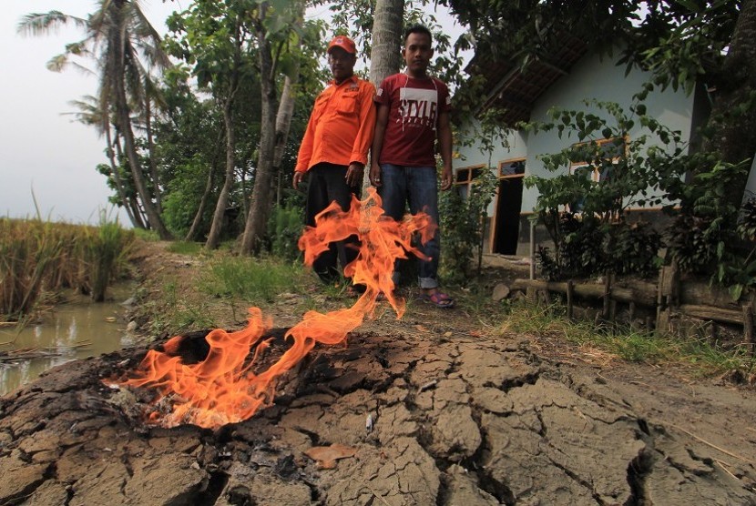 Petugas BPBD bersama warga mengamati api dari semburan gas yang muncul di permukiman di desa Sukaperna, Kecamatan Tukdana, Indramayu, Jawa Barat, Sabtu (30/12).