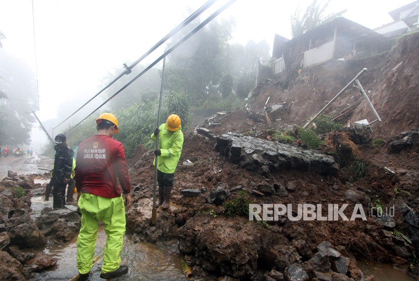 Petugas BPBD Kabupaten Bogor berusaha membersihkan material longsor yang menutupi jalur utama Puncak Bogor, Jawa Barat, Senin (5/2).