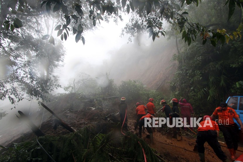 Petugas BPBD Kabupaten Bogor berusaha membersihkan material longsor yang menutupi jalur utama Puncak Bogor, Jawa Barat, Senin (5/2).