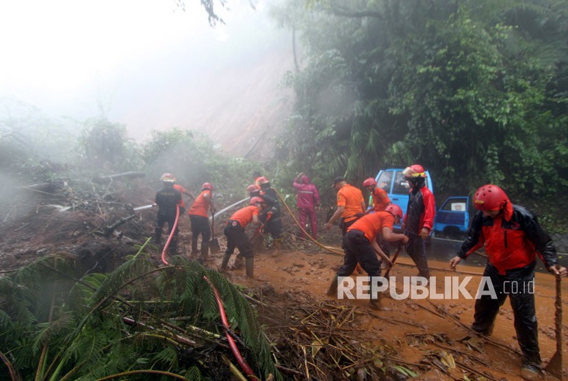 Petugas BPBD Kabupaten Bogor berusaha membersihkan material longsor yang menutupi jalur utama Puncak Bogor, Jawa Barat, Senin (5/2). 
