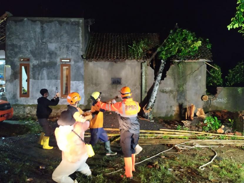 Petugas BPBD membersihkan sisa pohon tumbang yang menimpa rumah warga di Kelurahan Sukemenak, Kecamatan Purbaratu, Kota Tasikmalaya, Jumat (22/1) malam. Cuaca ekstrem yang terjadi di Kota Tasikmalaya pada Jumat sore mengakibatkan puluhan rumah warga rusak tersapu angin dan tertimpa pohon tumbang. 