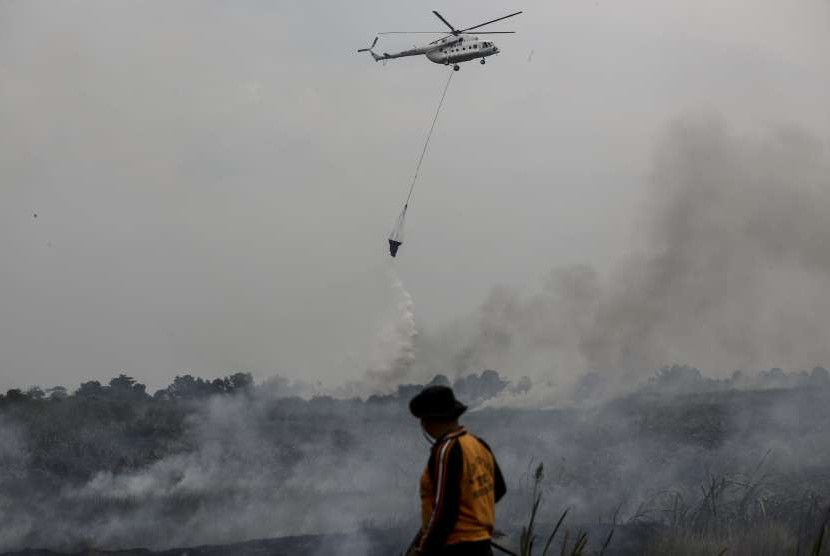 Petugas BPBD Provinsi Sumatera Selatan dibantu Helikopter MI-8Mtv milik Badan Nasional Penanggulangan Bencana (BNPB) melakukan pemadaman kebakaran lahan di Desa Rambutan, Banyuasin, Sumatra Selatan, Minggu (16/9). 