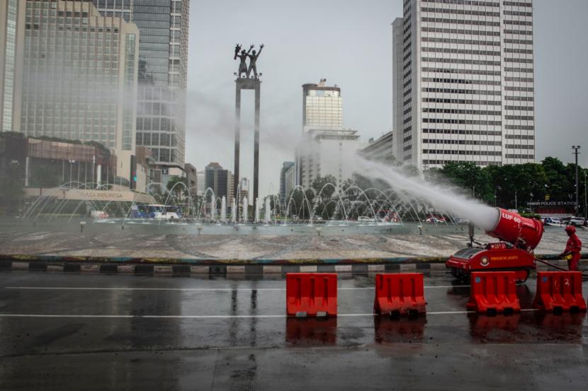 Petugas Damkar menyemprotkan cairan disinfektan di kawasan Bundaran HI, Jakarta, Ahad (22/3/2020).