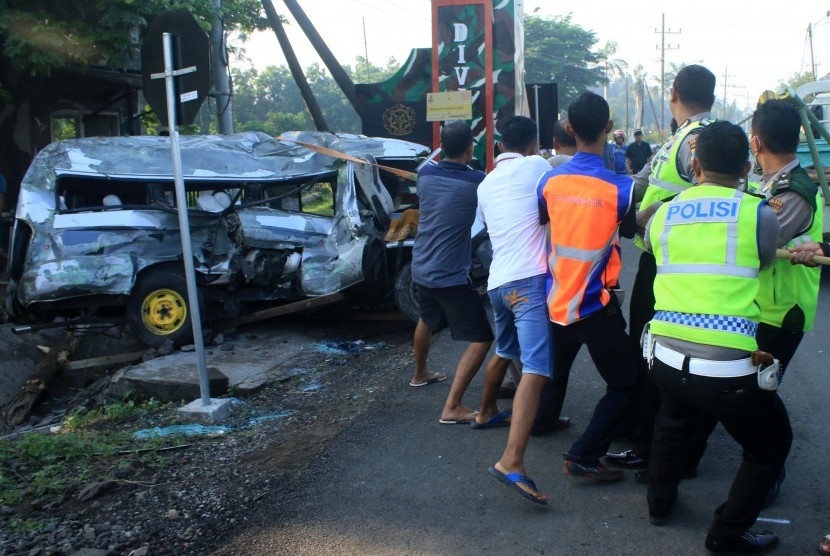 Petugas dan warga memindahkan mobil Mitsubisi L300 bernopol P 1264 DE yang ringsek akibat kecelakaan dengan kereta api di lintasan rel di Dusun Rohkepuh, Beji, Pasuruan, Jawa Timur, Rabu (9/1/2019).