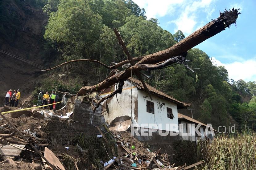 Petugas dan warga mengamati rumah yang rusak tertimbun longsoran bukit akibat gempa di kawasan Trunyan, Kintamani, Bangli, Bali, Sabtu (16/10/2021). Gempa bumi dengan magnitudo 4,8 SR yang terjadi di darat pada jarak delapan kilometer barat laut Karangasem dengan kedalaman 10 km pada Sabtu (16/10) pukul 04.18 Wita mengakibatkan sejumlah bangunan di Bali rusak dan tiga orang meninggal dunia. 