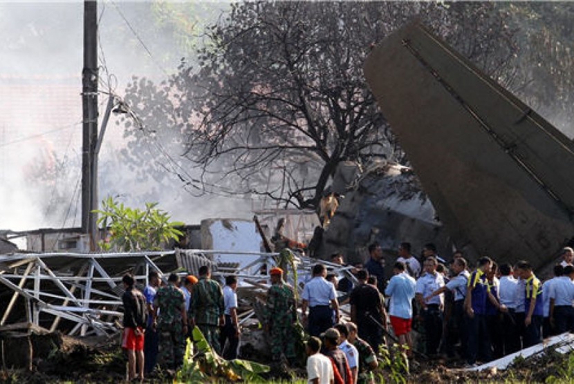 Petugas dan warga menyaksikan bangkai pesawat Fokker 27 yang jatuh dan terbelah di komplek perumahan Rajawali kawasan Lapangan Udara Halim Perdana Kusuma, Jakarta, Kamis (21/6). 