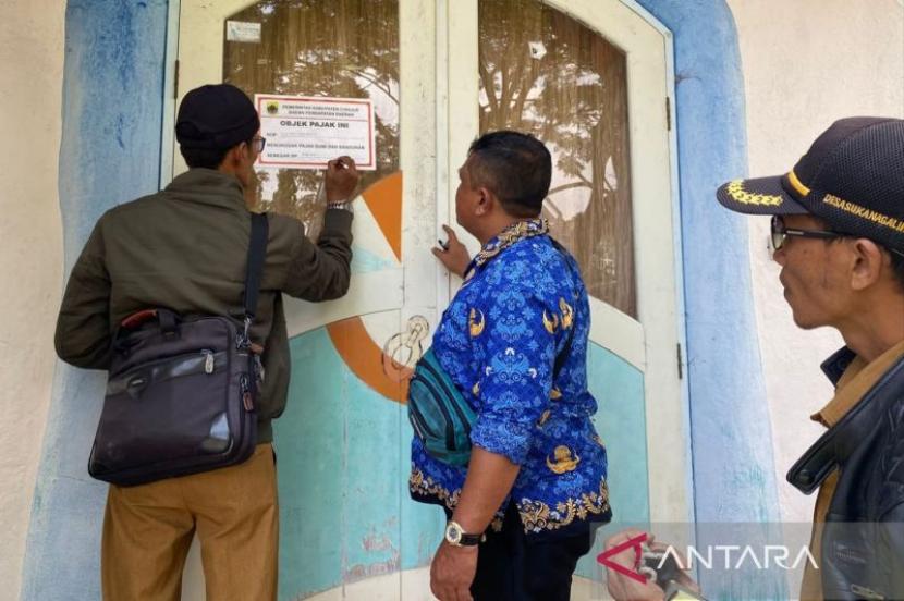 Petugas dari Badan Pendapatan Daerah (Bapenda) Kabupaten Cianjur, Jawa Barat, memasang stiker di vila yang menunggak pajak di Perumahan Kota Bunga, Kecamatan Cipanas.