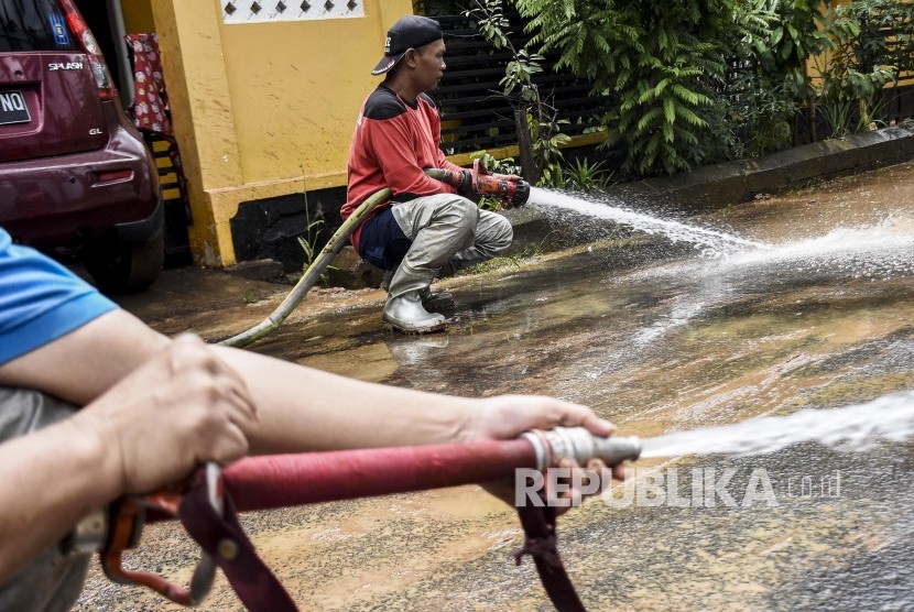 Petugas dari Dinas Pemadam Kebakaran Kota Bandung membersihkan lumpur pascabanjir di kawasan Kompleks Guruminda, Kelurahan Cisaranten Kulon, Kecamatan Arcamanik, Kota Bandung, Jumat (7/2).