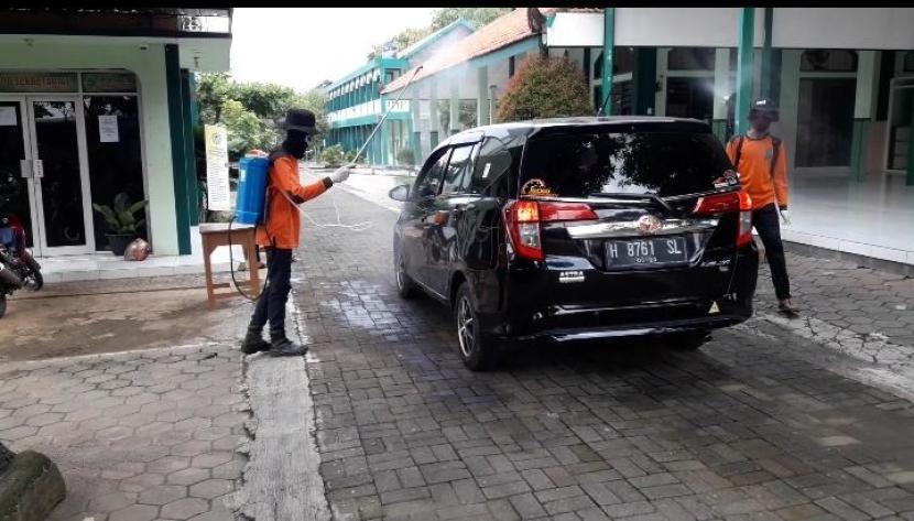 Petugas dari Hidayatullah Gerai Kudus melakukan penyemprotan disinfektan mobil orang santri SMP Hidayatullah Kudus yang menjemput anaknya.