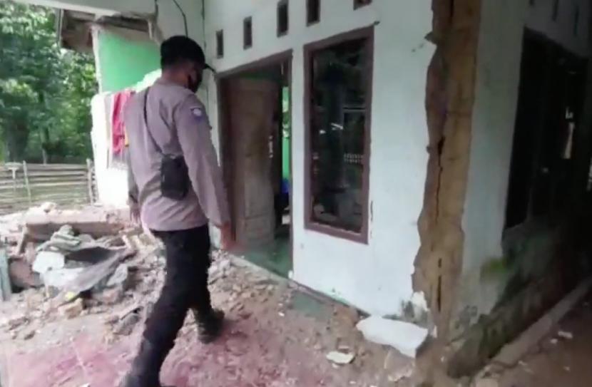Petugas dari kepolisian tengah melakukan pengecekan terhadap rumah yang rusak akibat terdampak gempa bumi.