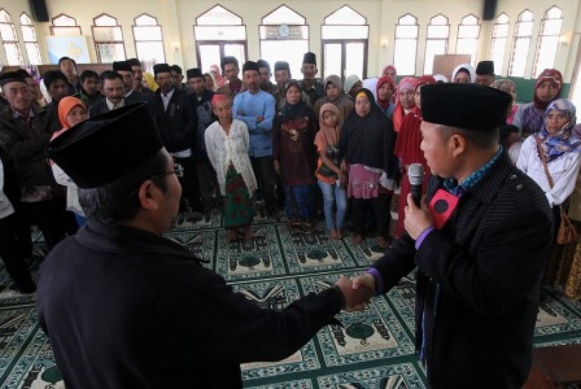 Petugas dari KUA mengajarkan cara ijab kabul kepada warga peserta pernikahan massal gratis di Masjid Mujahidin, Tosari, Pasuruan, Jawa Timur, Jumat (23/10). 