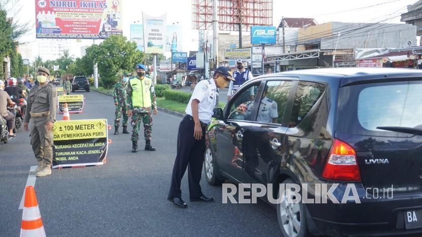 Petugas dari Polri, TNI, Dinas Perhubungan dan Pol PP mengecek kendaraan yang masuk ke Kota Padang di Check Poin depan Basko Padang dalam rangka penerapan Pembatasan Sosial Berskala Besar (PSBB) di Sumbar, Senin (28/4)|