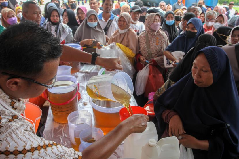 Petugas dari PT Pekebunan Nusantara V menuangkan minyak goreng curah ke dalam jeriken milik warga yang membeli minyak goreng murah di Pekanbaru, Riau, Rabu (13/7/2022). PTPN V menyalurkan sebanyak 28 ton minyak goreng curah murah seharga Rp12.000 per liter kepada warga Kota Pekanbaru. 