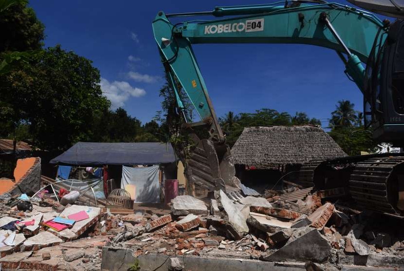 Petugas dengan alat berat merobohkan rumah yang rusak akibat gempa bumi di Kayangan, Lombok Utara, NTB, Minggu (12/8).
