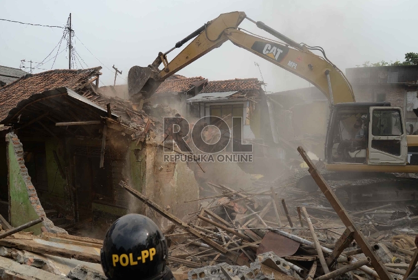 Petugas dengan alat berat merobohkan bangunan saat penggusuran pemukiman liar di Kampung Pulo, Jatinegara, Jakarta, Kamis (20/8).