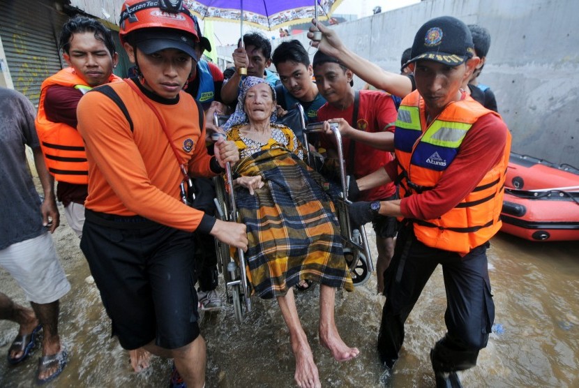 Petugas dengan dibantu warga mengevakuasi lansia yang terkena dampak banjir