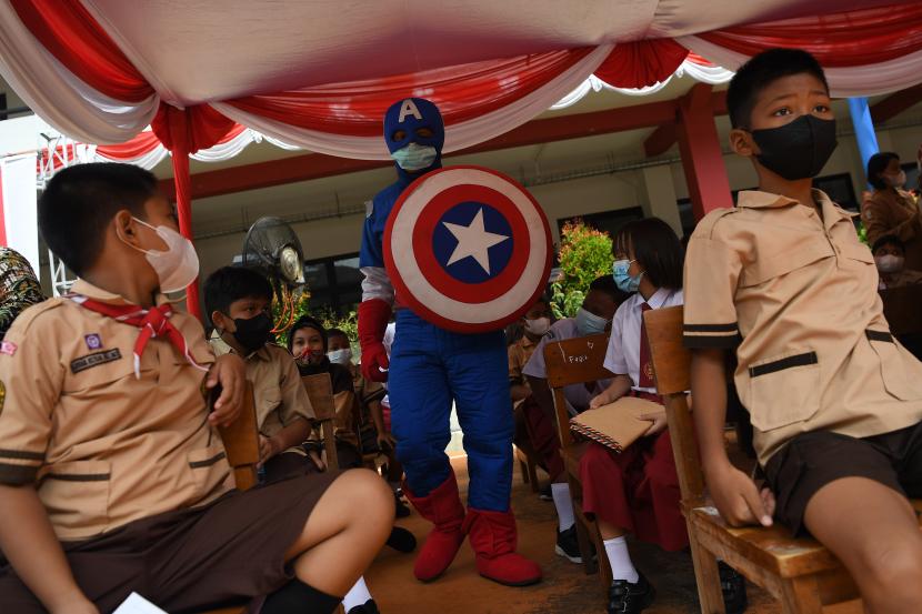 Petugas dengan kostum Captain Amerika menghibur sejumlah siswa sekolah dasar yang antre mendapatkan vaksinasi Covid-19 di kompleks SDN Cideng, Kecamatan Gambir, Jakarta Pusat, Rabu (15/12/2021).