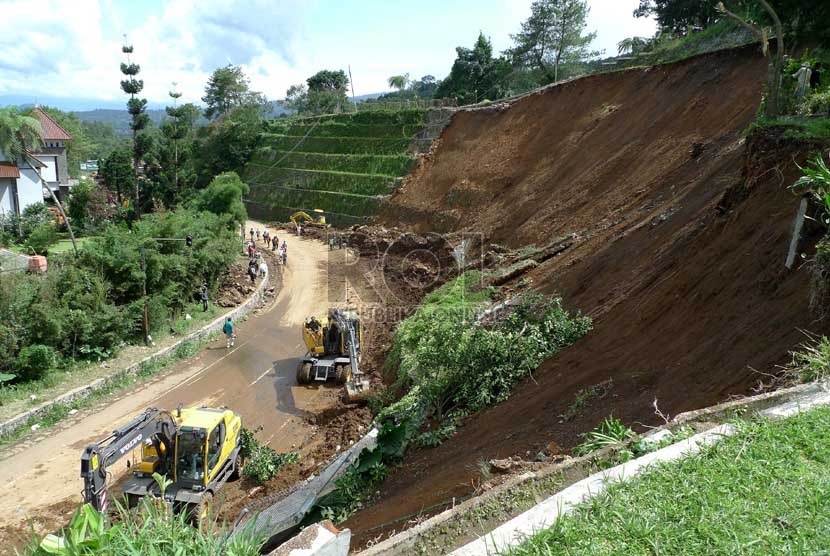 Petugas dengan menggunakan alat berat membersihkan sisa longsor tebing di Ciloto Puncak, Jabar,Kamis (10/1). (Republika/Musiron)