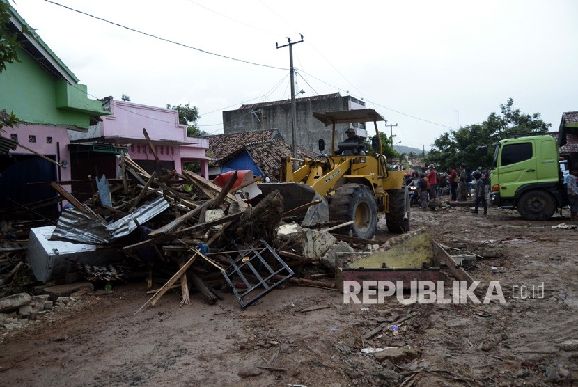 Petugas dengan menggunakan alat berat membersihkan sisa-sisa bangunan yang tersapu tsunami di jalan Desa Way Muli, Kecamatan Rajabasa, Lampung Selatan, Lampung, Ahad (23/12/2018). 