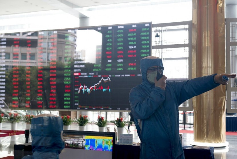Petugas dengan pakaian pelindung bekerja di depan layar yang menunjukkan pergerakan saham di Shanghai Stock Exchange, Shanghai, China. PBB serukan paket ekonomi untuk negara berkembang di tengah pandemi Covid-19. Ilustrasi. 