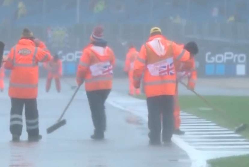 Petugas di lintasan sirkuit Silverstone, Inggris sedang membersihkan genangan air
