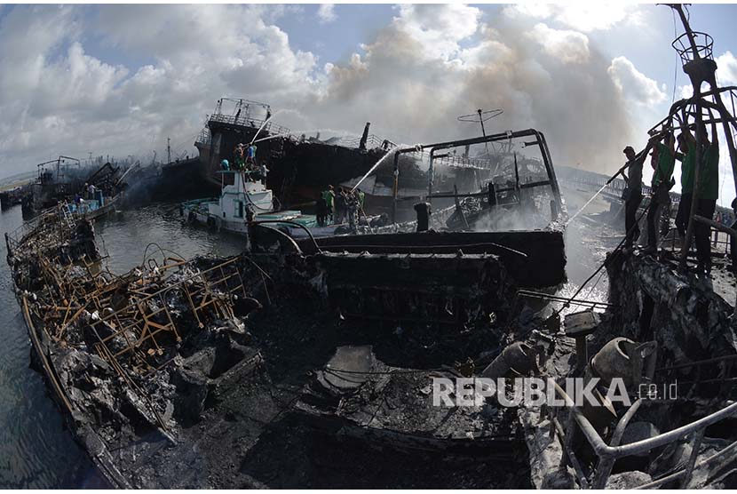 Petugas dibantu warga berusaha melakukan upaya pendinganan kapal ikan yang terbakar di Pelabuhan Benoa, Denpasar, Bali, Senin (9/7). 