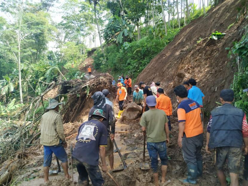 Petugas dibantu warga sekitar melakukan pembersihan akses jalan yang tertimpa longsor di Desa Bugel, Kecamatan Ciawi, Kabupaten Tasikmalaya, Rabu (10/6).