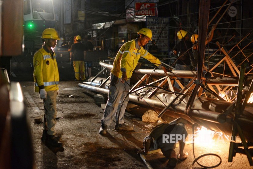 Petugas Dinas Bina Marga mengevakuasi papan reklame yang rubuh di Jalan Warung Buncit Raya, Jakarta Selatan, Minggu (1/12).  Reklame yang berukuran antara 7,5 hingga 10 meter tingginya rubuh pukul 19.30 tersebut menimpa satu mobil yang melintas, namun dipastikan tidak ada korban jiwa.