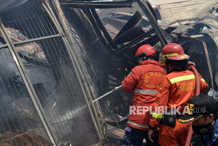 Petugas Dinas Kebakaran (Damkar) Kota Bekasi berupaya memadamkan sisa api yang membakar pabrik gudang tempat pembuatan palet kayu di Jalan Agus Salim, Kota Bekasi, Jawa Barat, Selasa (19/11/2019).