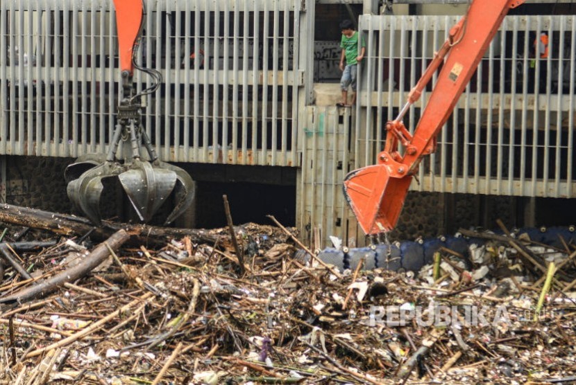 Petugas Dinas Kebersihan DKI Jakarta menggunakan alat berat membersihkan sampah di pintu air Manggarai, Jakarta. Ketinggian air di Manggarai dan Karet sudah memasuki level waspada 