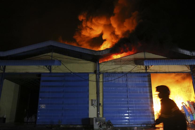 Petugas Dinas Pemadam Kebakaran melewati gedung yang terbakar (ilustrasi).