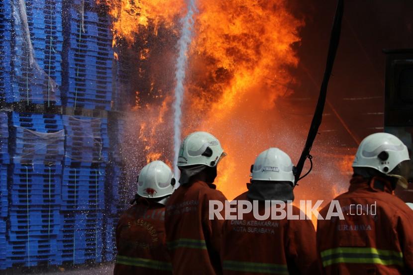 Petugas Dinas Pemadam Kebakaran Kota Surabaya berusaha memadamkan api yang membakar sebuah pabrik dan gudang palet plastik di kawasan Tandes, Surabaya, Jawa Timur, Rabu (31/3/2021). Puluhan kendaraan pemadam kebakaran dikerahkan untuk memadamkan kebakaran itu. 