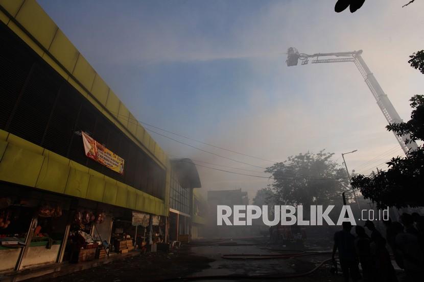 Petugas Dinas Pemadam Kebakaran Kota Surabaya melakukan pembasahan Pasar Kembang yang terbakar di Surabaya, Jawa Timur, Ahad (22/8/2021). Sekitar 23 kendaraan pemadam kebakaran dikerahkan untuk memadamkan kebakaran pasar tradisional yang meludeskan lapak-lapak di lantai dua di pasar tersebut.