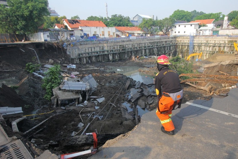 Petugas Dinas Pemadam Kebakaran Kota Surabaya memeriksa lokasi tanah ambles di Jalan Raya Gubeng, Surabaya, Jawa Timur, Rabu (19/12/2018).