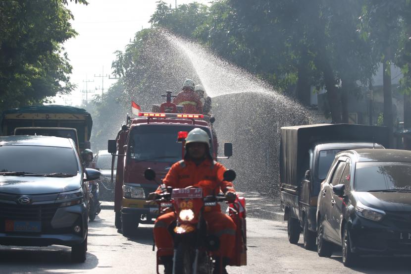 Petugas Dinas Pemadam Kebakaran Kota Surabaya menyemprotkan larutan disinfektan di Surabaya, Jawa Timur, Jumat (20/3/2020).