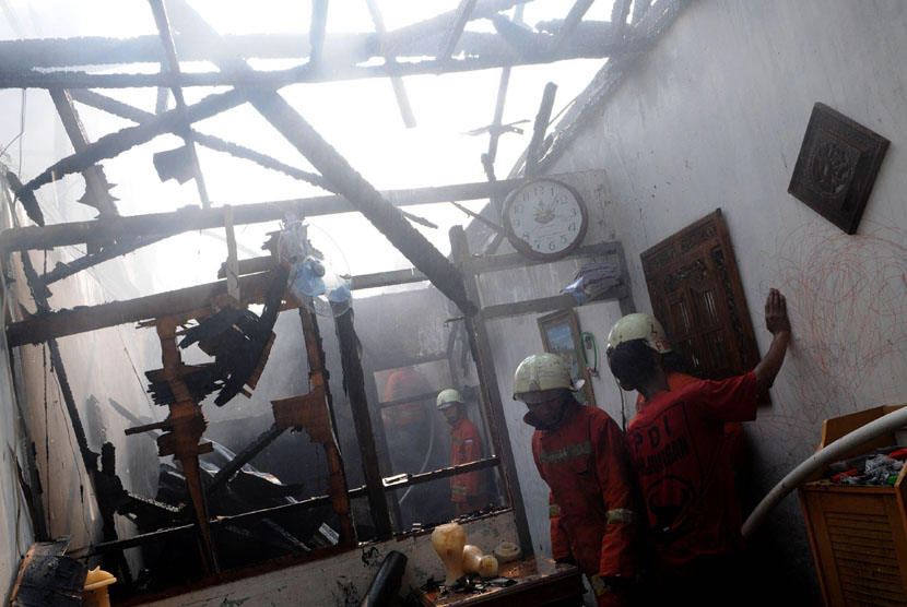  Petugas Dinas Pemadam Kebakaran memadamkan sisa api yang menghanguskan permukiman warga di Manggarai, Jakarta Selatan, Selasa (17/7).   (Prayogi/Republika)