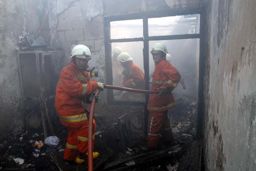  Petugas Dinas Pemadam Kebakaran memadamkan sisa api yang menghanguskan permukiman warga di Manggarai, Jakarta Selatan, Selasa (17/7).   (Agung Fatma Putra/Republika)