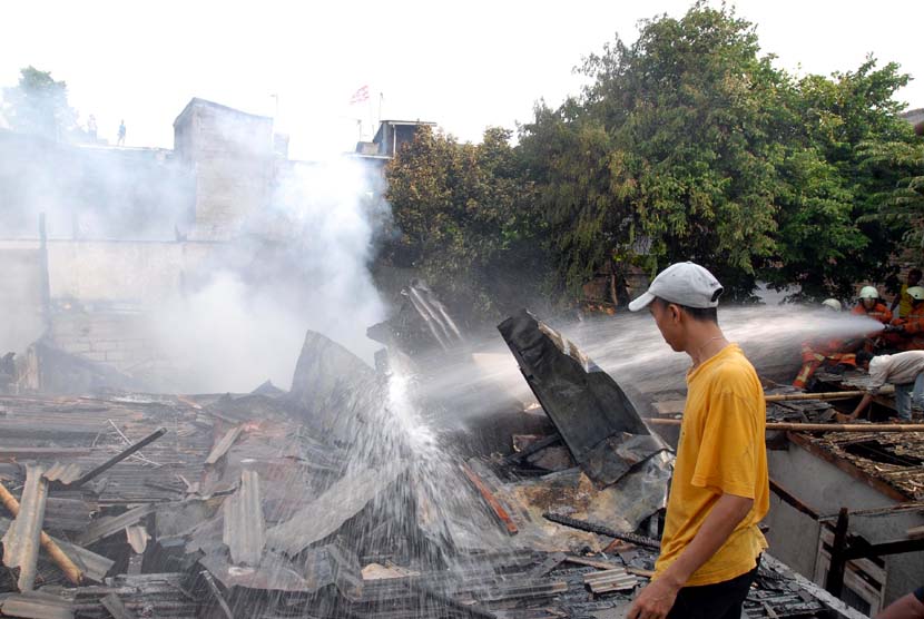  Petugas Dinas Pemadam Kebakaran memadamkan sisa api yang menghanguskan permukiman warga di Manggarai, Jakarta Selatan, Selasa (17/7).   (Agung Fatma Putra/Republika)