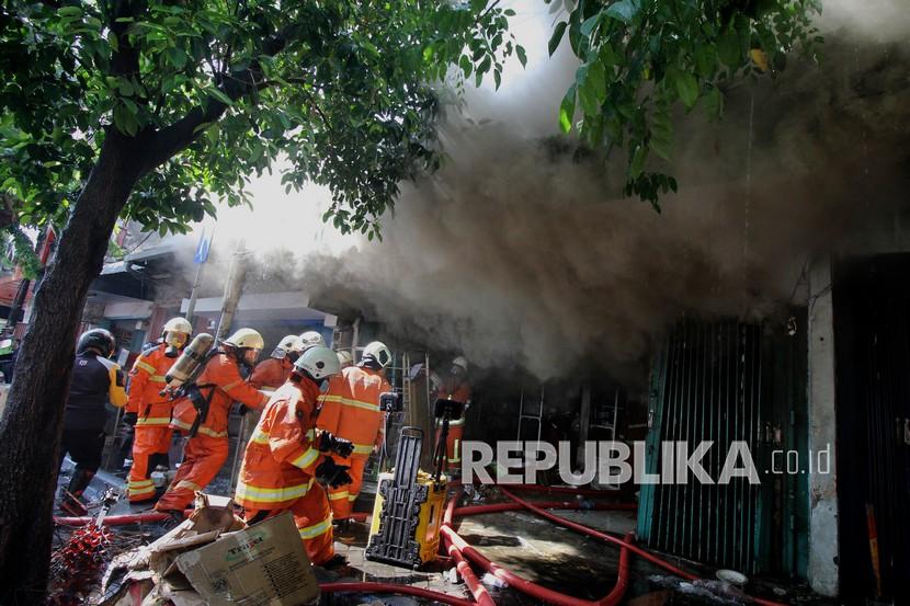 Petugas Dinas Pemadam Kebakaran memadamkan toko elektronik yang terbakar di Jalan Kranggan, Surabaya, Jawa Timur, Minggu (30/8/2020). Sekitar 22 kendaraan pemadam kebakaran dikerahkan untuk memadamkan kebakaran yang menewaskan lima orang di dalam toko tersebut. 
