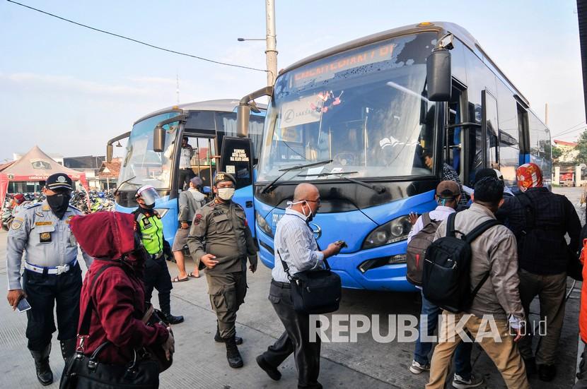 Petugas mengatur jarak penumpang dari Kota Bogor yang ingin menuju Jakarta sebelum naik bus gratis bantuan Pemprov DKI.