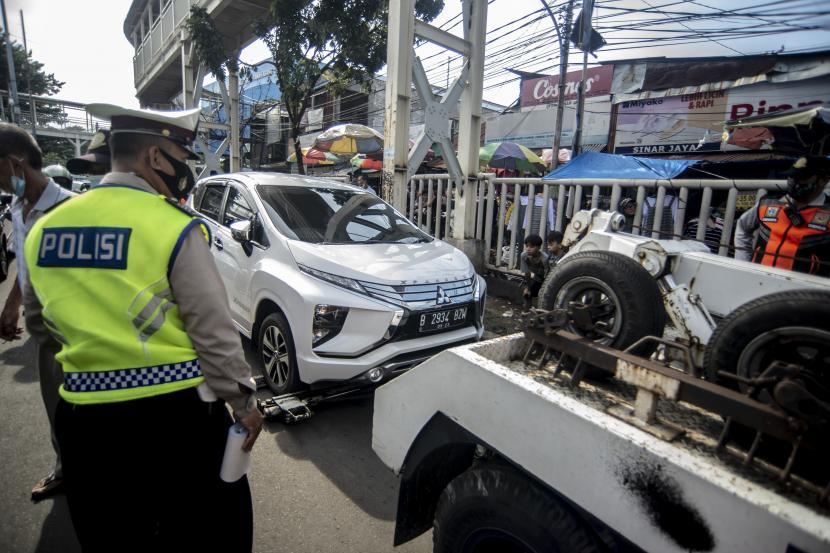 Petugas Dinas Perhubungan DKI Jakarta menderek sebuah mobil yang parkir sembarangan.